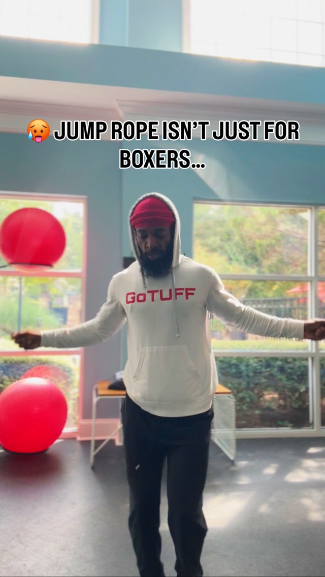 Coach Chez jumping rope in a white GoTUFF hoodie and red cap